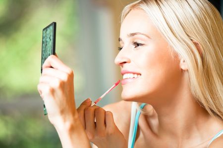 Young happy woman applying lipstickの写真素材