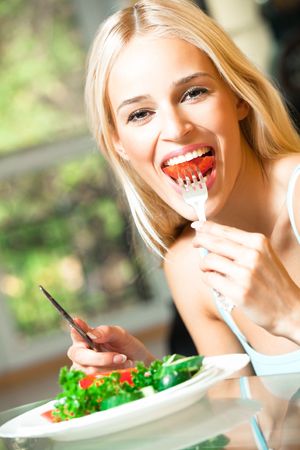 Young happy smiling woman eating vegetarian saladの写真素材