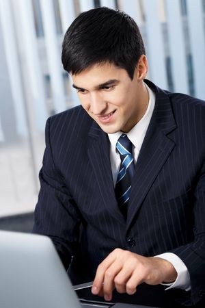 Successful businessman with laptop at officeの写真素材