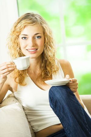 Young happy smiling woman drinking coffee, at homeの写真素材