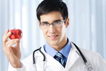 Happy smiling doctor with apple, at officeの写真素材