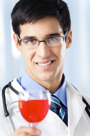 Happy smiling doctor with red wine, at office. Focus on doctor.の写真素材