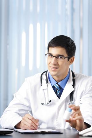 Happy doctor with bottle of drug, at officeの写真素材
