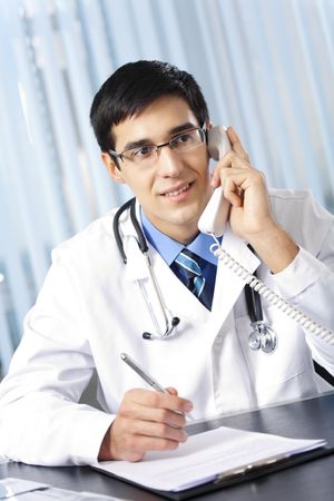 Successful doctor with phone, at workplaceの写真素材