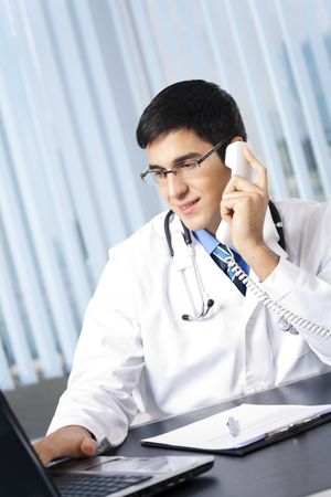 Successful doctor with phone and laptop, at officeの写真素材