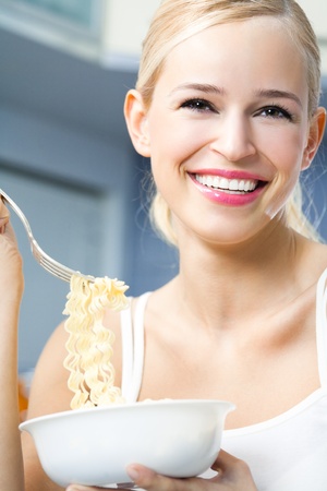 Happy smiling woman eating spaghetti indoorsの写真素材
