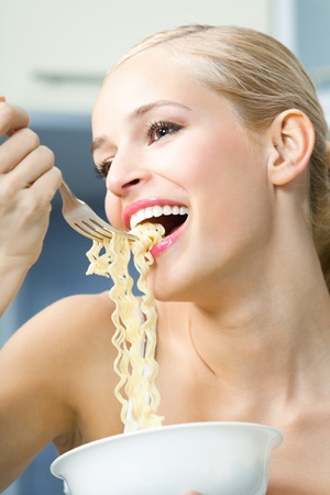 Happy woman eating spaghetti indoorsの写真素材