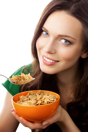 Portrait of young smiling woman eating muesli or cornflakes, isolated on white backgroundの写真素材