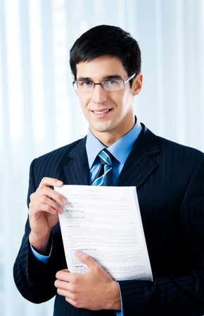Happy smiling businessman showing document or contract, at officeの写真素材