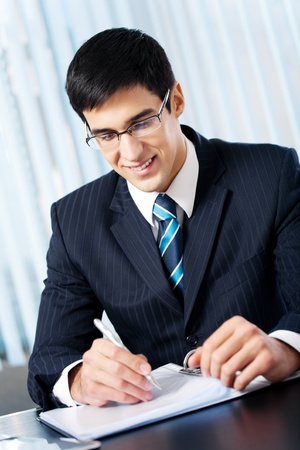 Portrait of writing smiling businessman working at officeの写真素材