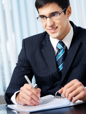 Portrait of writing smiling businessman working at officeの写真素材