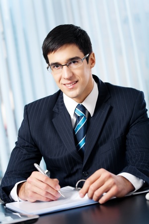 Portrait of writing smiling businessman working at officeの写真素材