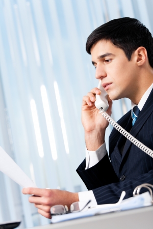 Successful businessman with phone and document at officeの写真素材