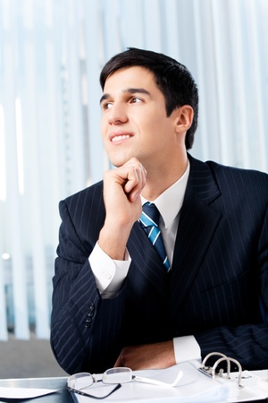Portrait of thinkihg businessman with documents at officeの写真素材