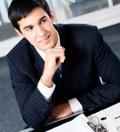 Portrait of thinkihg businessman with documents at officeの写真素材