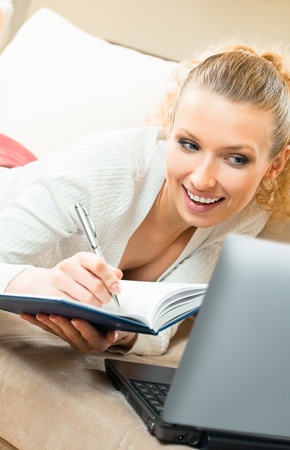 Young happy smiling woman working with organizer and laptop, at homeの写真素材