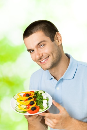 Portrait of young happy smiling man with plate of salad, outdoorsの写真素材