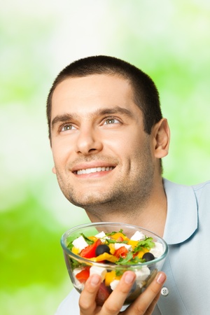 Portrait of young happy man eating salad, outdoorsの写真素材