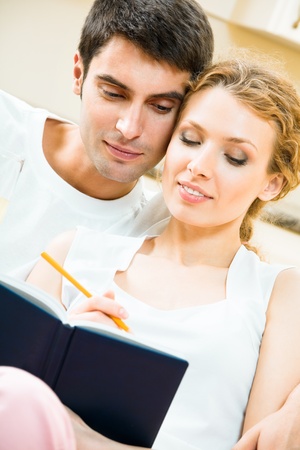 Young attractive happy smiling couple with notebook or organizer at homeの写真素材