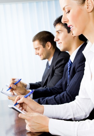Three happy smiling businesspeople at meeting, presentation or conferenceの写真素材