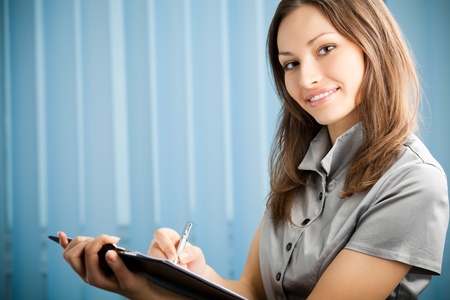 Portrait of writing happy smiling businesswoman working at office. You can use left part for slogan, big text or banner.の写真素材