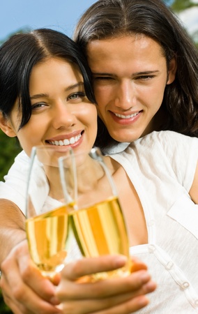 Young happy smiling attractive amorous couple celebrating with champagne together, outdoorsの写真素材