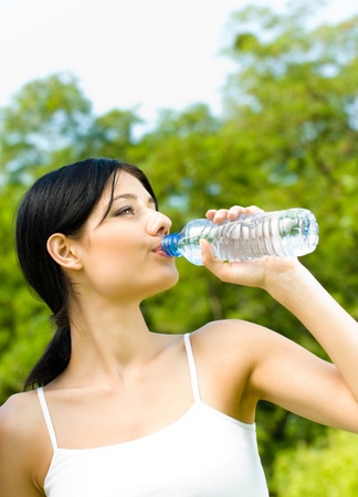 Young woman drinking water at workout, outdoorsの写真素材