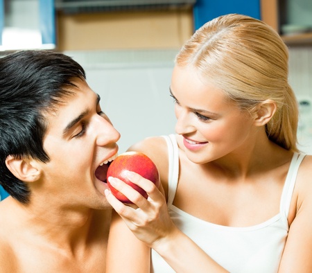Young happy couple eating apple at homeの写真素材