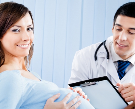 Portrait of happy smiling doctor and pregnant young woman, at officeの写真素材