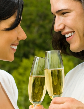 Young happy smiling cheerful attractive couple celebrating with glasses of champagne, outdoorの写真素材