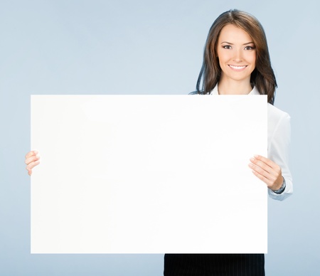Happy smiling young business woman showing blank signboard, over blue backgroundの写真素材