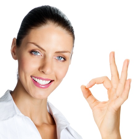 Cheerful beautiful young business woman showing okay gesture, isolated over white backgroundの写真素材