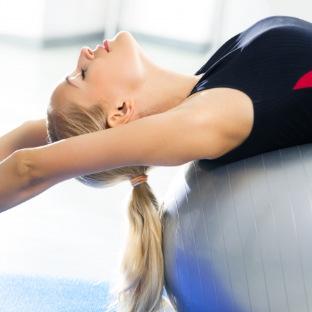 Young happy woman doing fitness exercises with fit ball at homeの写真素材