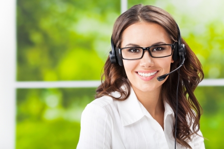 Portrait of happy smiling cheerful beautiful young support phone operator in headset, at office, with copyspaceの写真素材