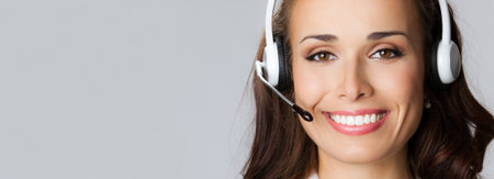 Portrait of happy smiling cheerful customer support phone operator in headset, over gray background,...