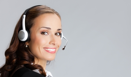 Portrait of happy smiling cheerful customer support phone operator in headset, over gray background, with copyspaceの写真素材