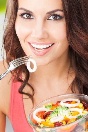 Portrait of happy smiling young woman with vegetarian vegetable salad, outdoorsの写真素材