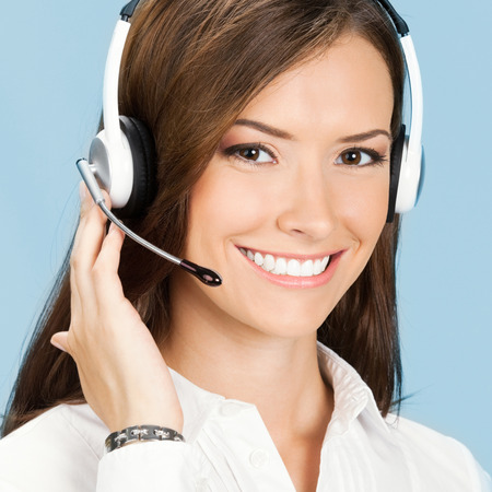 Portrait of happy smiling cheerful customer support phone operator in headset, over blue backgroundの写真素材