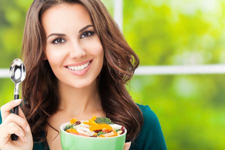 Young happy smiling beautiful woman with salad, outdoor, with copyspaceの写真素材