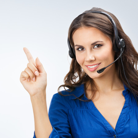 Portrait of happy smiling cheerful beautiful young support phone operator showingの写真素材