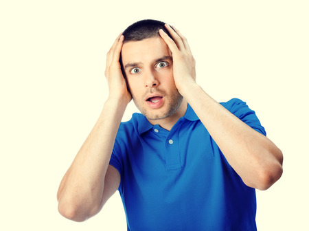 Portrait of expressive surprised or shocked young attractive handsome man in blue casual t-shirt clothing, looking at cameraの写真素材