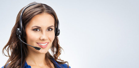 Portrait of happy smiling young support phone operator or businesswomen in headset, with blank copyspace area for slogan or text