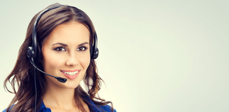 Cheerful smiling young support phone operator or businesswomen in headset, with blank copyspace area...