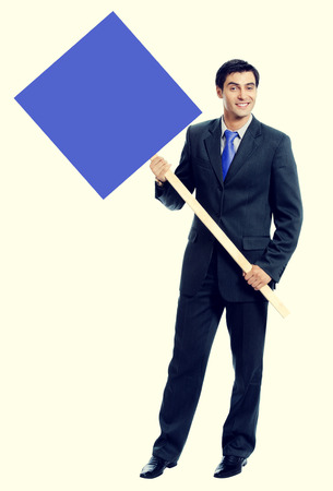 smiling young businessman in blue tie, showing blank signboard with blank copyspace area for text or sloganの写真素材