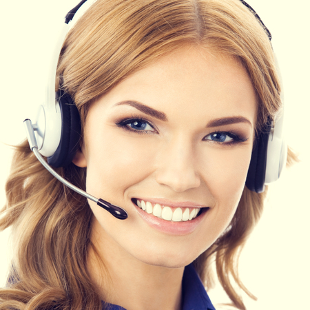 Portrait of happy smiling beautiful young female support phone operator or phone worker in headset and blue clothing. Customer service assistance concept.の写真素材