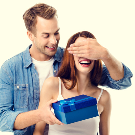 Happy couple with gift box, close to each other, with smile. Caucasian models in love, relationship, dating, flirting, lovers, romantic concept.の写真素材