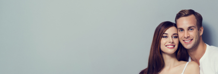 Portrait of young smiling couple, close to each other and looking at camera. Horizontal banner composition. Copyspace for slogan or text message.の写真素材