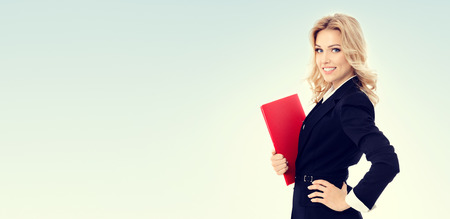 Portrait of young happy smiling businesswoman with red folder, with blank copyspace area for advertising, text or slogan. Success in business, job and education concept.の写真素材