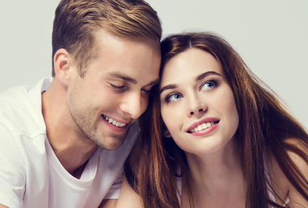Portrait of young couple, looking at you. Caucasian models - love, relationship, dating, happy lovers, concept shot, against grey, with copyspace for slogan or text message.  Horizontal banner composition.の写真素材