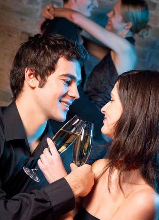 Young happy amorous couple with glasses of champagne on romantic date at restaurant or club. Love, party and date concept.の写真素材